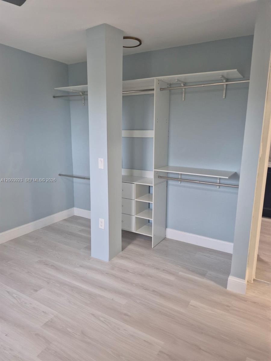 A walk-in closet features light blue walls, white shelving, and light wood-look flooring — 1231 NW 101st St # 2, Miami FL 33147, MIAMI, FL