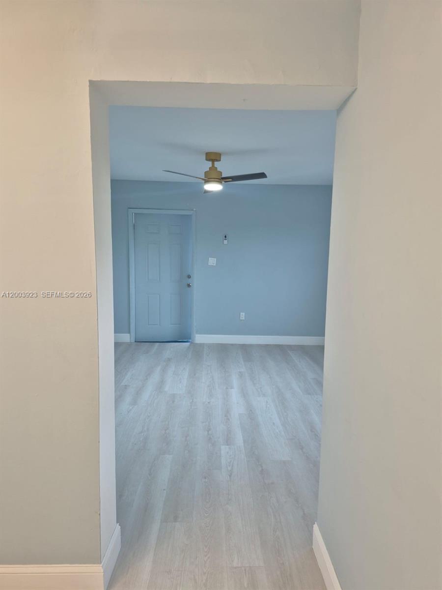 A doorway leads into a room with light-colored wood-look flooring, blue walls, and a ceiling fan — 1231 NW 101st St # 2, Miami FL 33147, MIAMI, FL