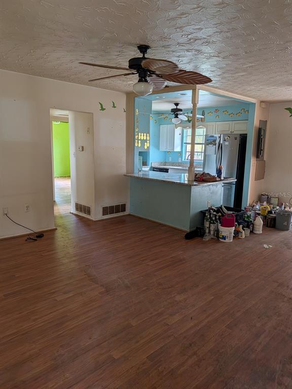 A living room with wood-look flooring features a kitchen island and a ceiling fan — 604 HAMLIN STREET, NOKOMIS, FL