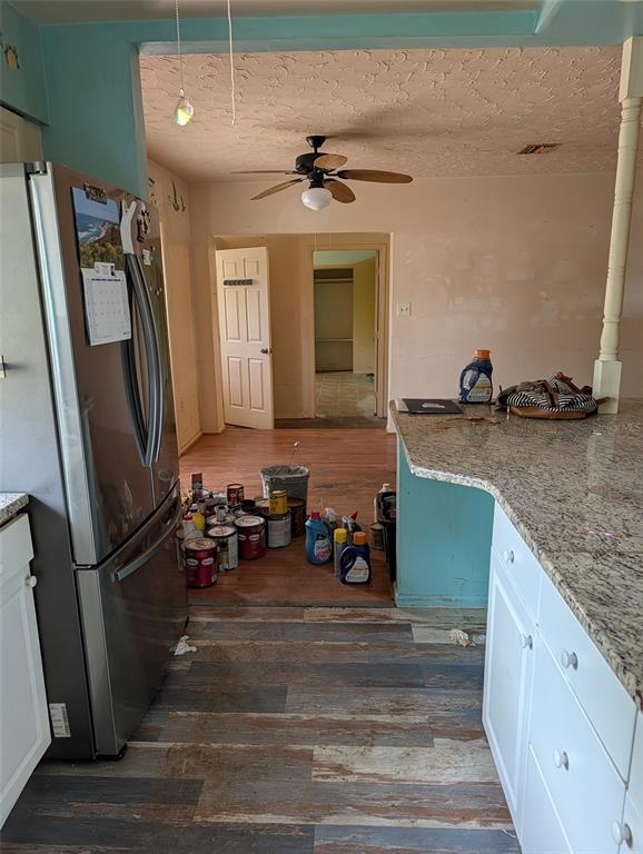 A kitchen with stainless steel appliances, granite countertops, and wood-look flooring leads into a hallway — 604 HAMLIN STREET, NOKOMIS, FL