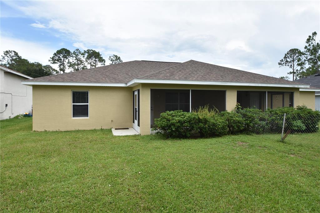 The rear exterior of a single-story house features a screened-in porch and a grassy yard — 7 RYARBOR DRIVE UNIT B, PALM COAST, FL