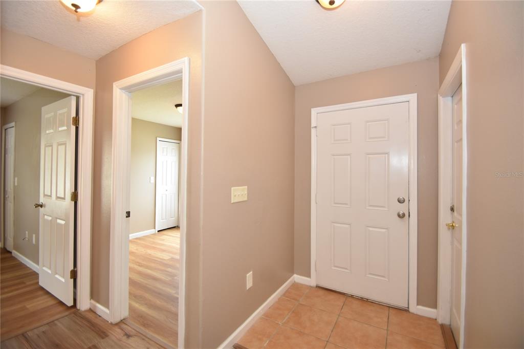 An entryway with a white front door, tiled floor, and doorways leading to other rooms — 7 RYARBOR DRIVE UNIT B, PALM COAST, FL
