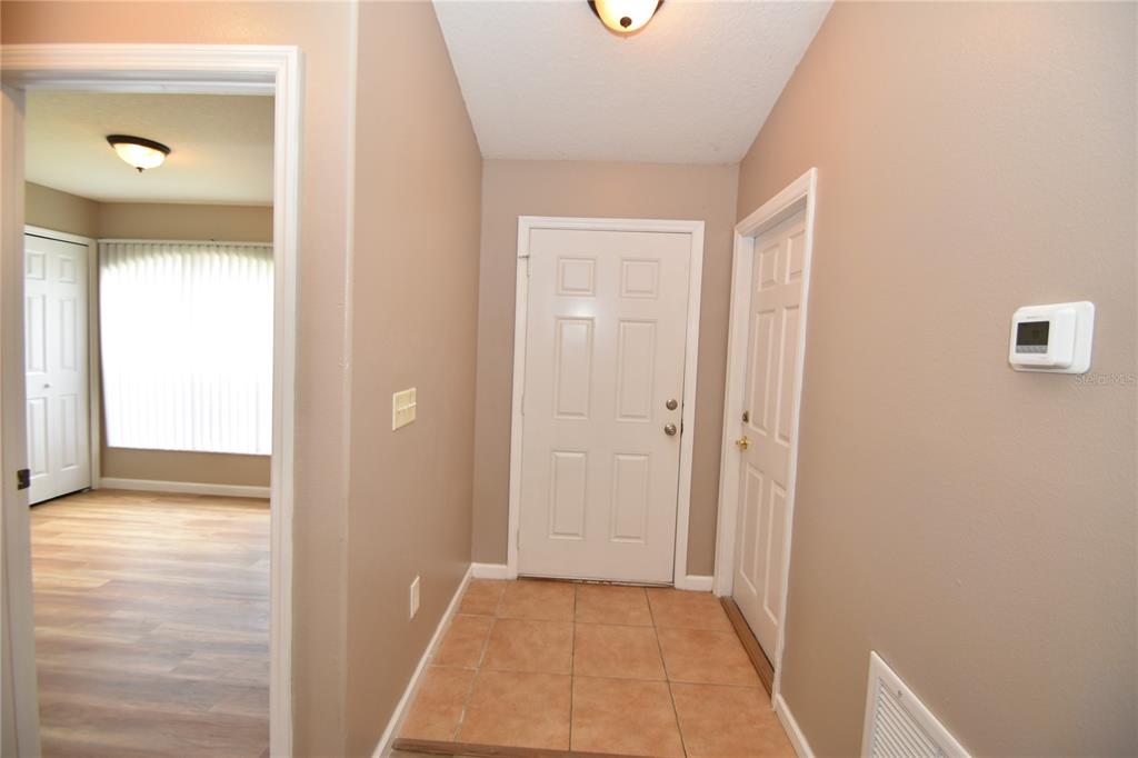 An entryway features a white front door, tile flooring, and a doorway leading to a room — 7 RYARBOR DRIVE UNIT B, PALM COAST, FL
