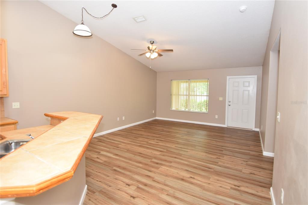 An open living area features wood-look flooring, a ceiling fan, and a kitchen breakfast bar — 7 RYARBOR DRIVE UNIT B, PALM COAST, FL