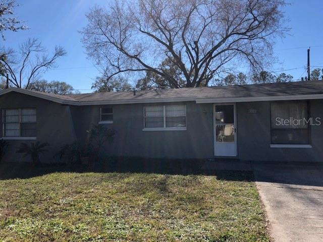 A single-story gray house with a concrete driveway and a large tree in the yard — 3222 ACACIA STREET, LUTZ, FL
