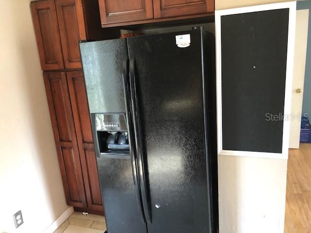 A black side-by-side refrigerator stands next to wooden cabinets and a wall-mounted chalkboard — 3222 ACACIA STREET, LUTZ, FL