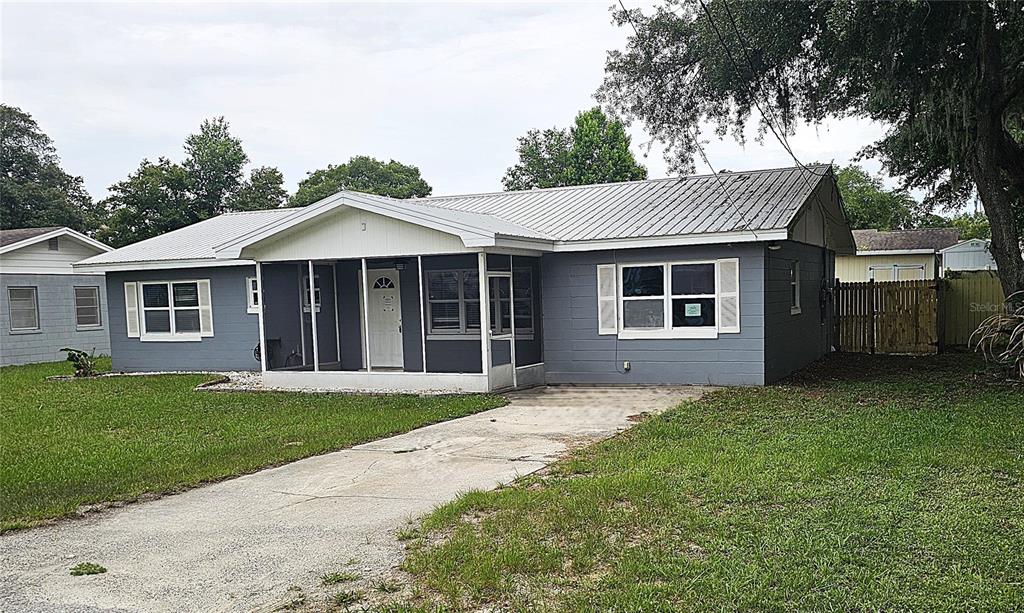 A single-story gray house with a metal roof and a screened-in front porch — 314 WOODLAND DRIVE, EUSTIS, FL
