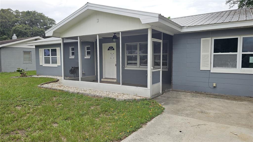 A gray house with a white-framed screened-in front porch and a metal roof — 314 WOODLAND DRIVE, EUSTIS, FL