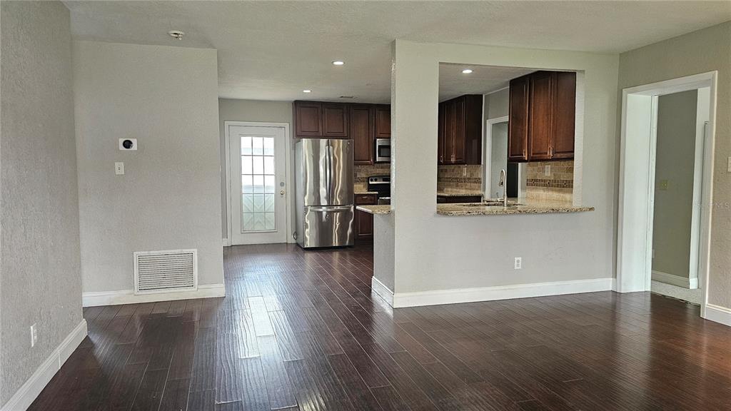A kitchen with dark wood cabinets and stainless steel appliances opens to a living area — 314 WOODLAND DRIVE, EUSTIS, FL