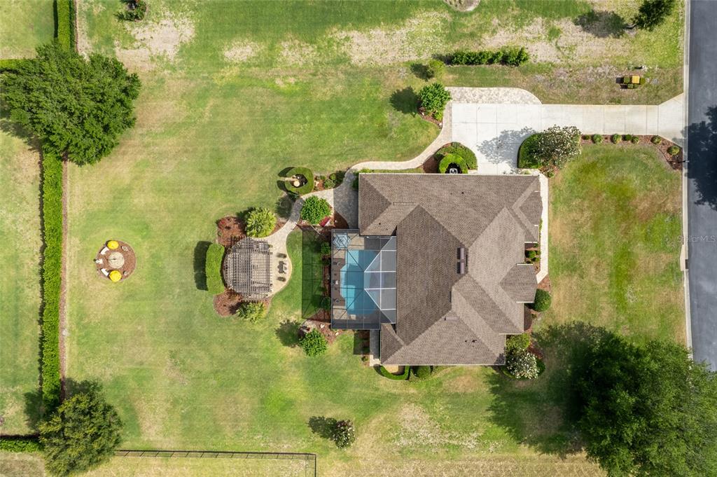 A single-story house with a tan stucco exterior, stone accents, and a brown shingled roof — 7830 SE 25TH AVENUE, OCALA, FL