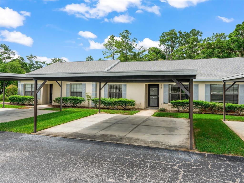 A single-story residential building features a concrete carport and a front entrance with shutters — 1701 SE 24TH ROAD UNIT 1702, OCALA, FL