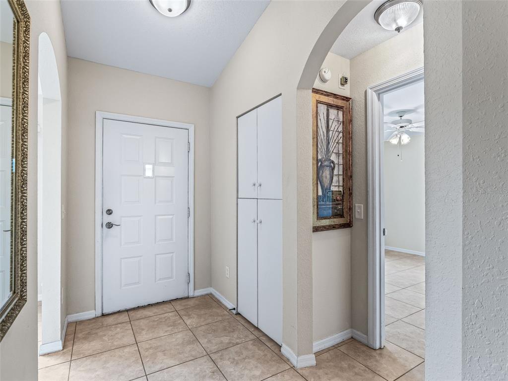 An entryway features a white front door, tiled flooring, a tall storage cabinet, and arched doorways — 1701 SE 24TH ROAD UNIT 1702, OCALA, FL