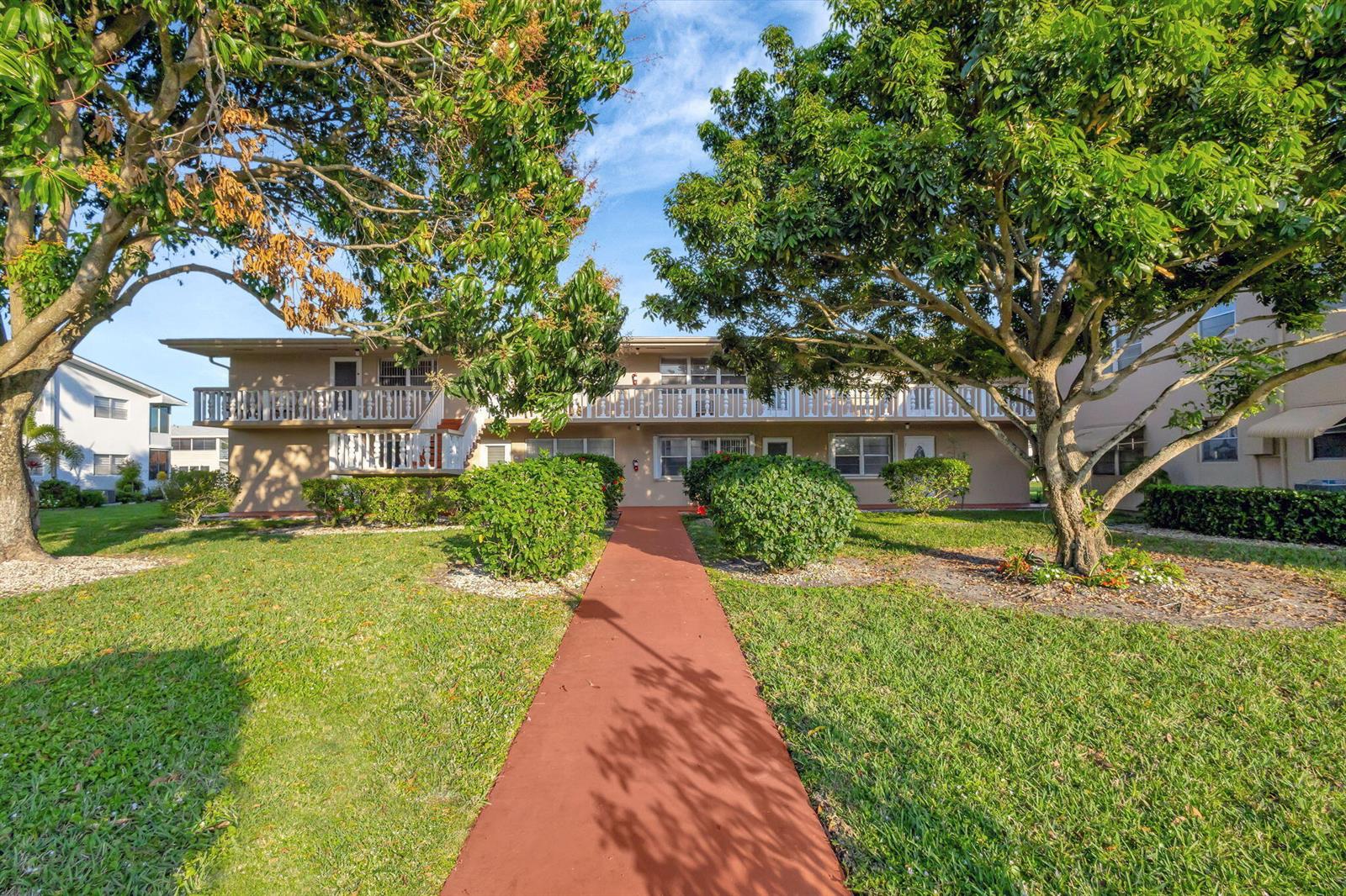 A two-story apartment building with a red walkway leading to the entrance — 121 Bedford E, West Palm Beach FL 33417, WEST PALM BEACH, FL