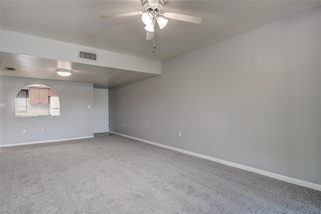 A living room with gray carpet, light gray walls, and a ceiling fan — 860 S VILLAGE DRIVE N UNIT 106, ST PETERSBURG, FL