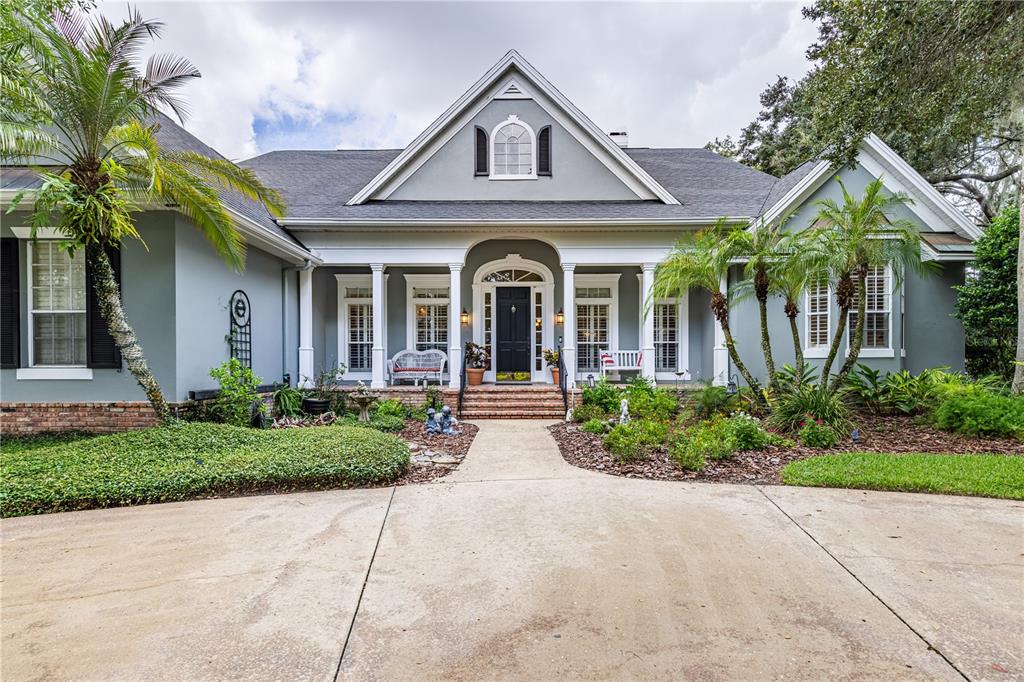 A covered patio features a brick fireplace, wicker furniture, and a wood-paneled vaulted ceiling — 34317 WINDLEY CIRCLE, EUSTIS, FL