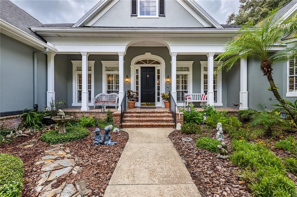 A covered patio features a brick fireplace, a bar with stools, and wicker furniture — 34317 WINDLEY CIRCLE, EUSTIS, FL
