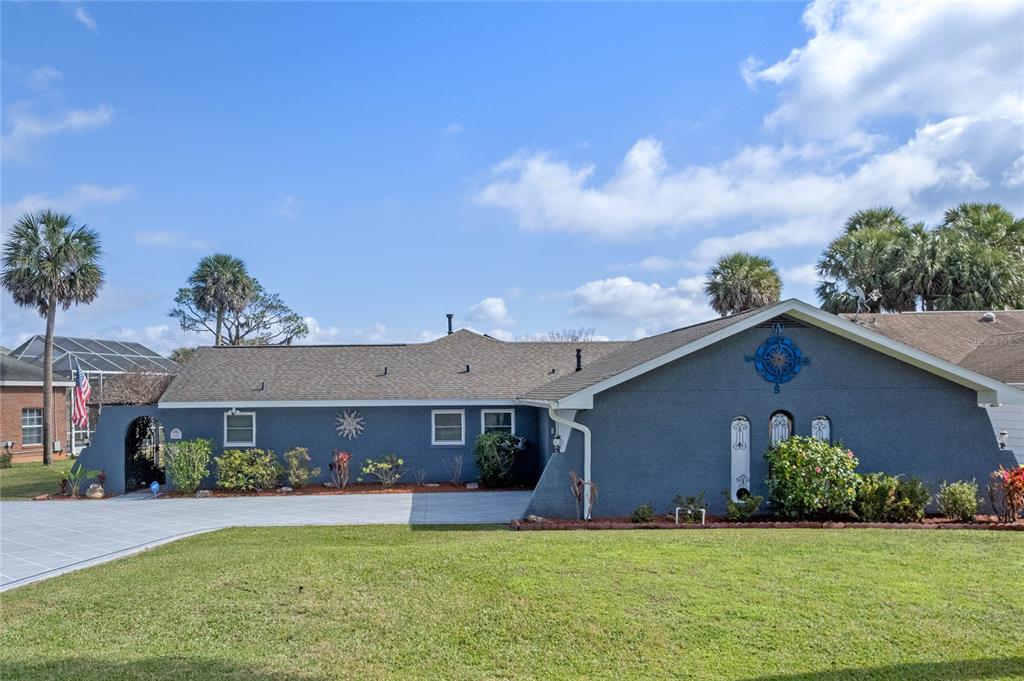 A single-story house with blue stucco walls, a gray roof, and a compass wall decoration — 1102 N PALMETTO STREET, LEESBURG, FL