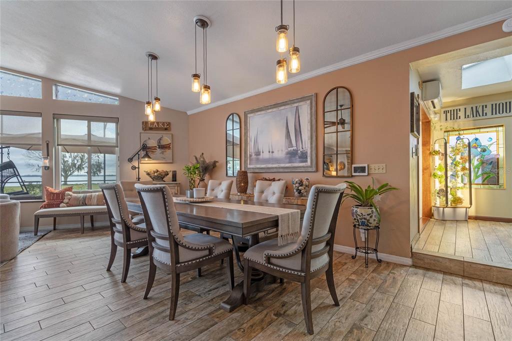 A dining room features a wooden table, upholstered chairs, pendant lighting, and lake-view windows — 1102 N PALMETTO STREET, LEESBURG, FL