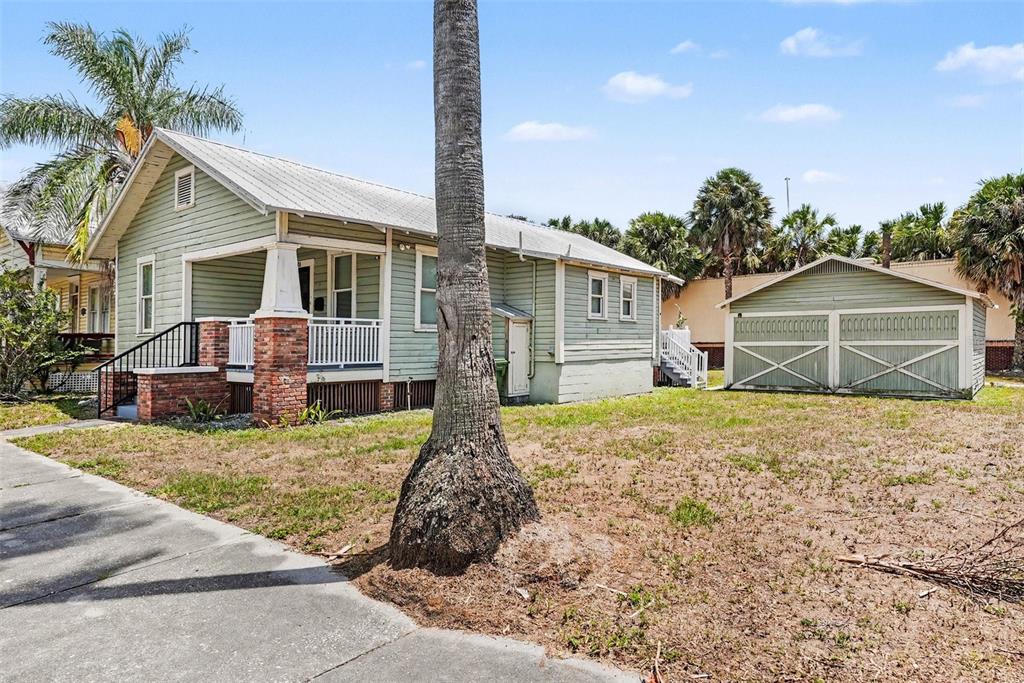 A light green house with a front porch and a detached garage on a grassy lot — 1601 E 15TH AVENUE, TAMPA, FL