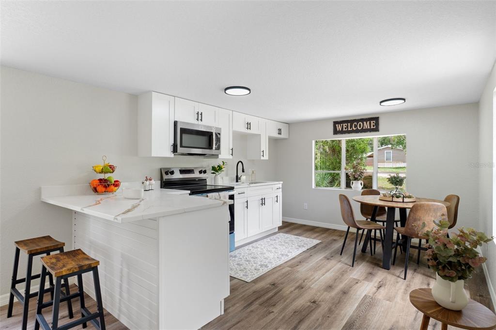 A kitchen with white cabinets, a breakfast bar, and an adjacent dining area — 3320 N HOLIDAY DRIVE, CRYSTAL RIVER, FL