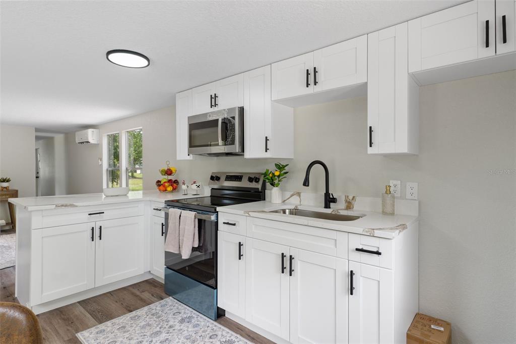 A kitchen features white cabinets, black hardware, stainless steel appliances, and a sink with a faucet — 3320 N HOLIDAY DRIVE, CRYSTAL RIVER, FL