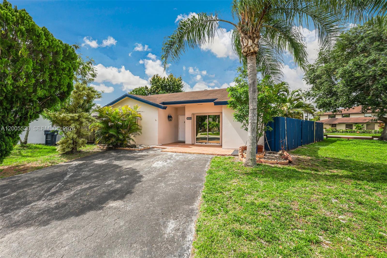 A single-story house with a paved driveway, a palm tree, and a blue fence — 13890 SW 43rd Ter, Miami FL 33175, MIAMI, FL