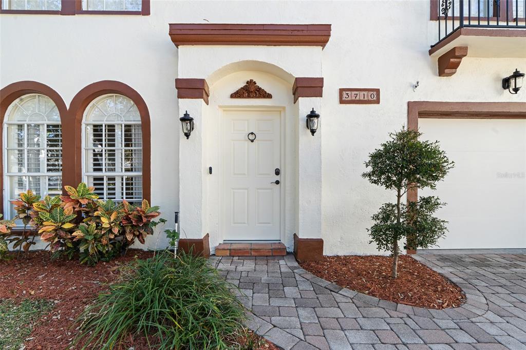 A white front door with a decorative archway sits beside a garage and arched windows — 3710 W LEONA STREET, TAMPA, FL