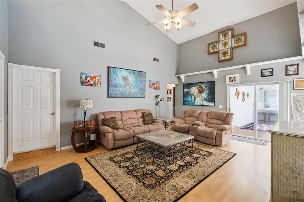 A living room features vaulted ceilings, large windows, a television, and a brown sectional sofa — 5405 BAYBROOK AVENUE, ORLANDO, FL