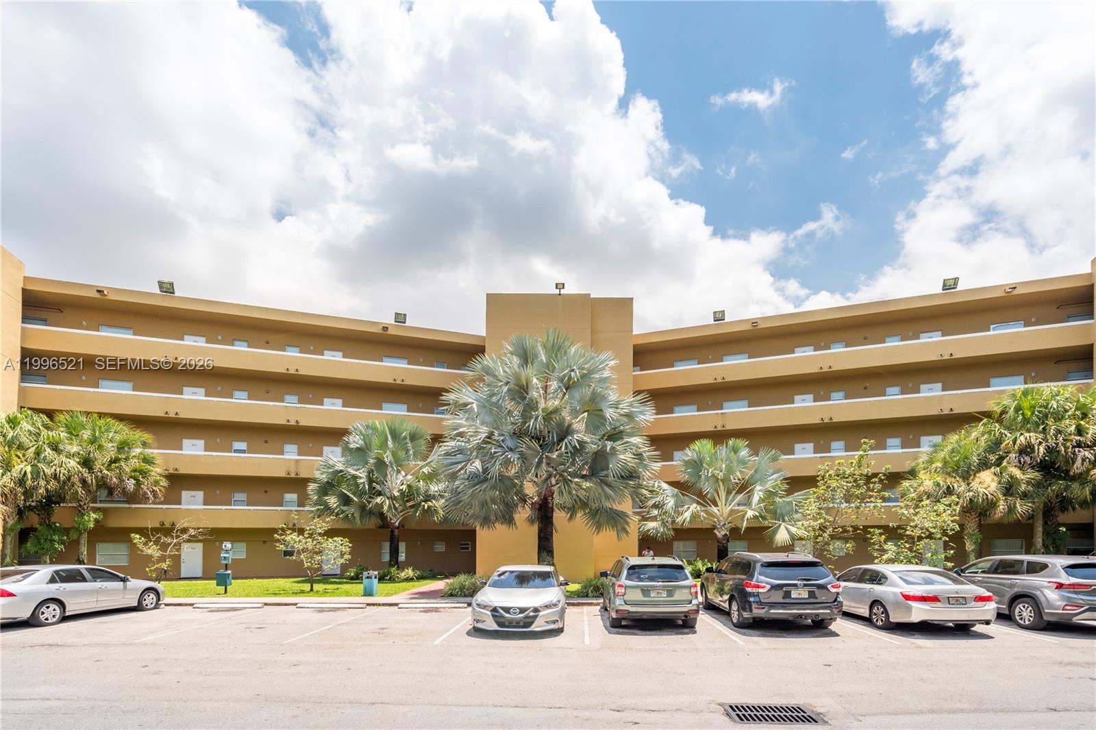 A multi-story tan apartment building features curved balconies and a parking lot in front — 4137 Stirling Rd # 507, Dania Beach FL 33314, DANIA BEACH, FL
