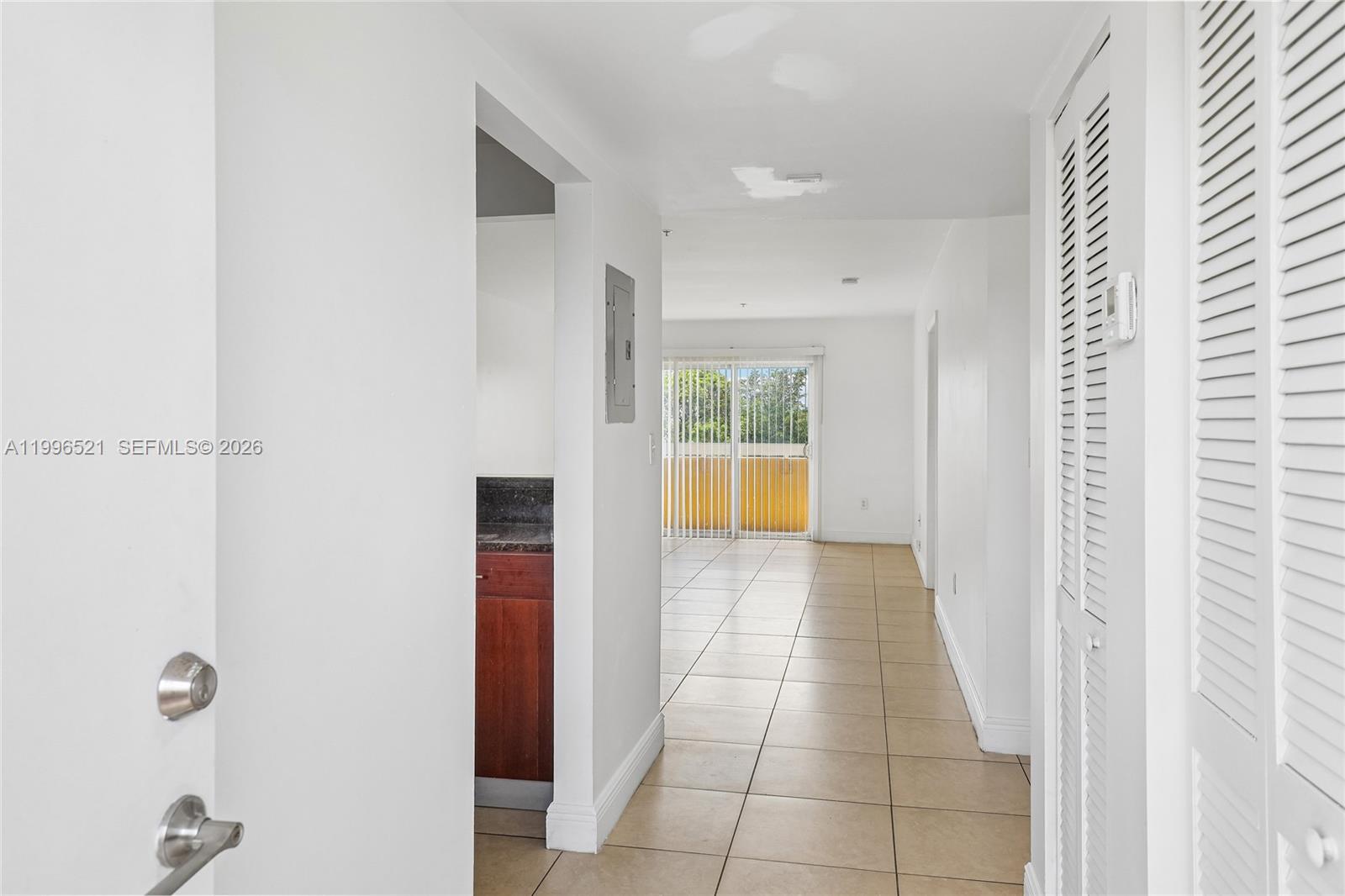 A tiled hallway leads past a kitchen toward a living area with sliding glass doors — 4137 Stirling Rd # 507, Dania Beach FL 33314, DANIA BEACH, FL