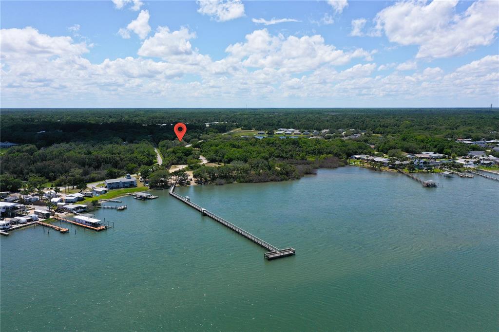 An aerial view shows a long wooden pier extending into a body of water — 317 WATER LANDING DRIVE, OAK HILL, FL