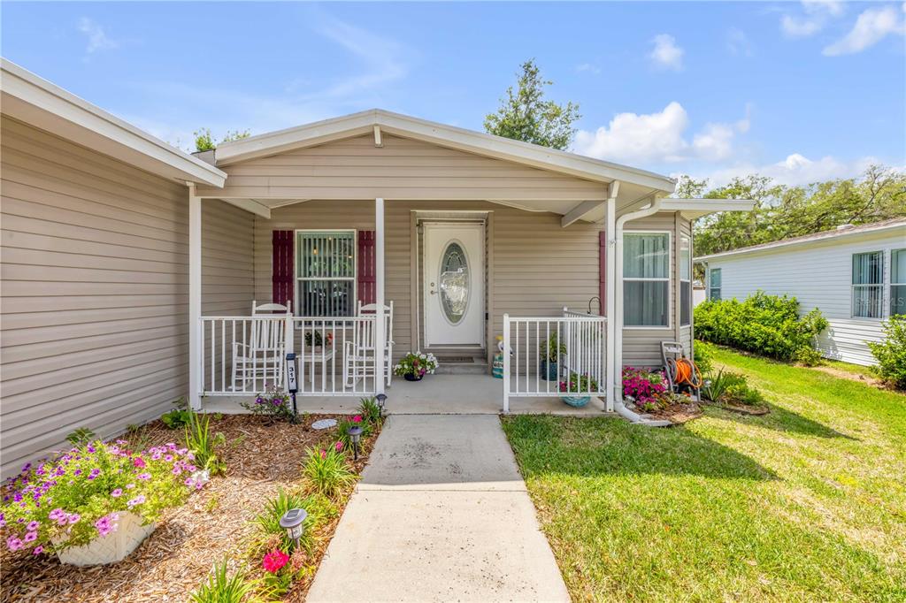 The exterior of a single-story house features a covered front porch with white railings — 317 WATER LANDING DRIVE, OAK HILL, FL
