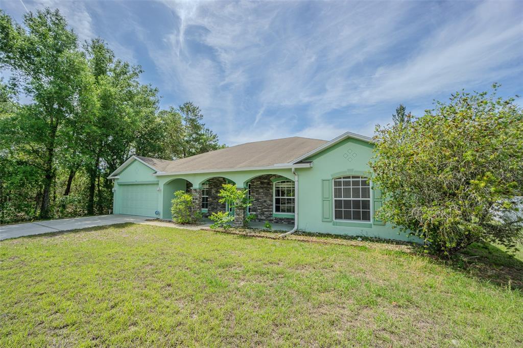 A single-story house with light green stucco, stone accents, and an attached garage — 6283 LORRAINE LANE, SPRING HILL, FL