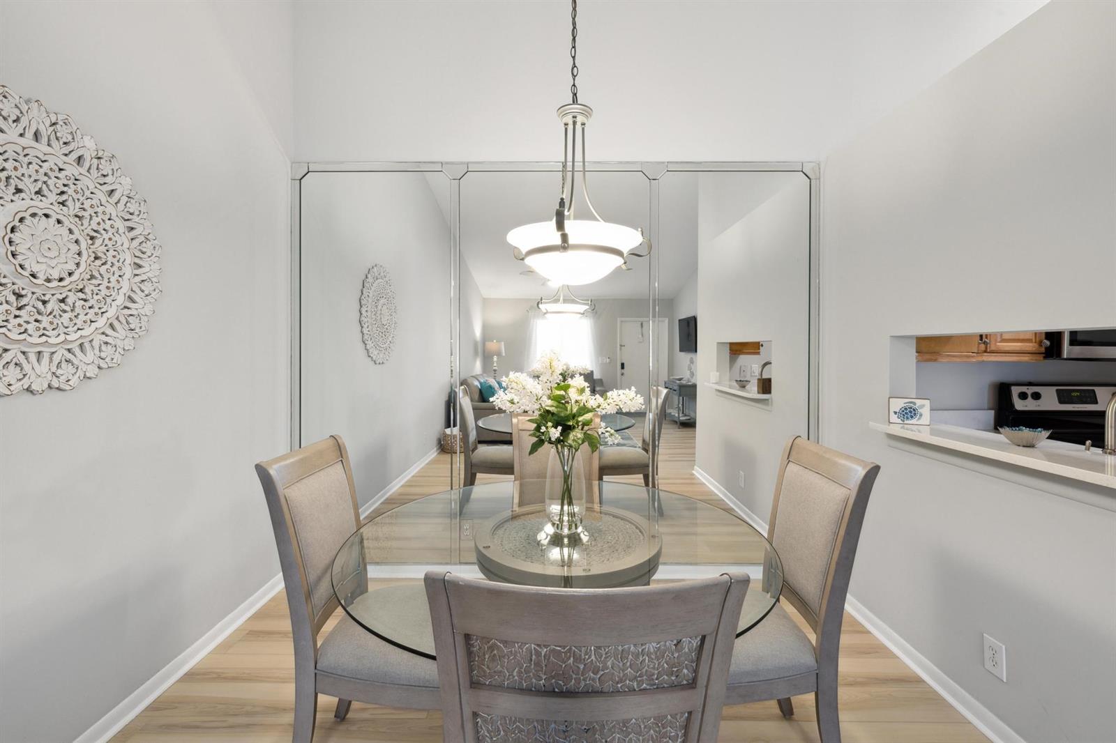 A dining area features a glass-topped table, upholstered chairs, a mirrored wall, and pendant lighting — 6271 Chasewood Drive # F, Jupiter FL 33458, JUPITER, FL