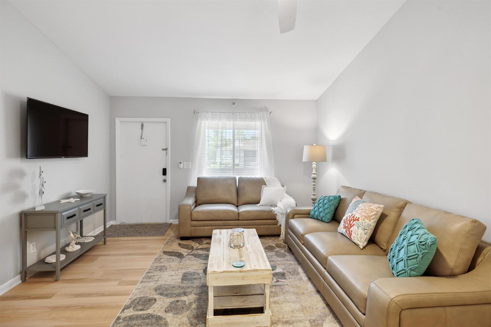 A living room features two tan leather sofas, a wooden coffee table, and a console table — 6271 Chasewood Drive # F, Jupiter FL 33458, JUPITER, FL