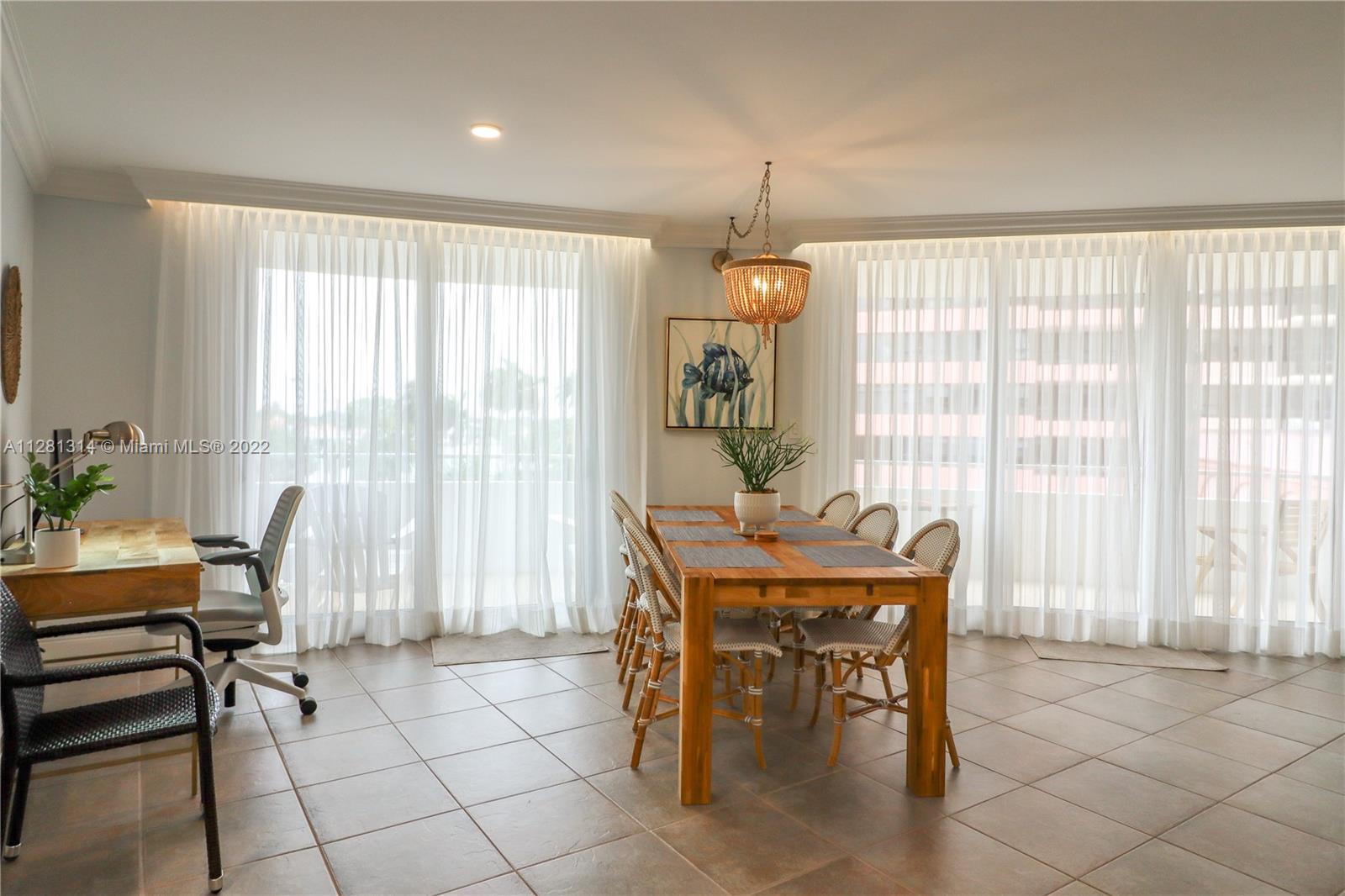A dining area with a wooden table and chairs sits beside a home office space — 5161 Collins Ave # 404, Miami Beach FL 33140, MIAMI BEACH, FL