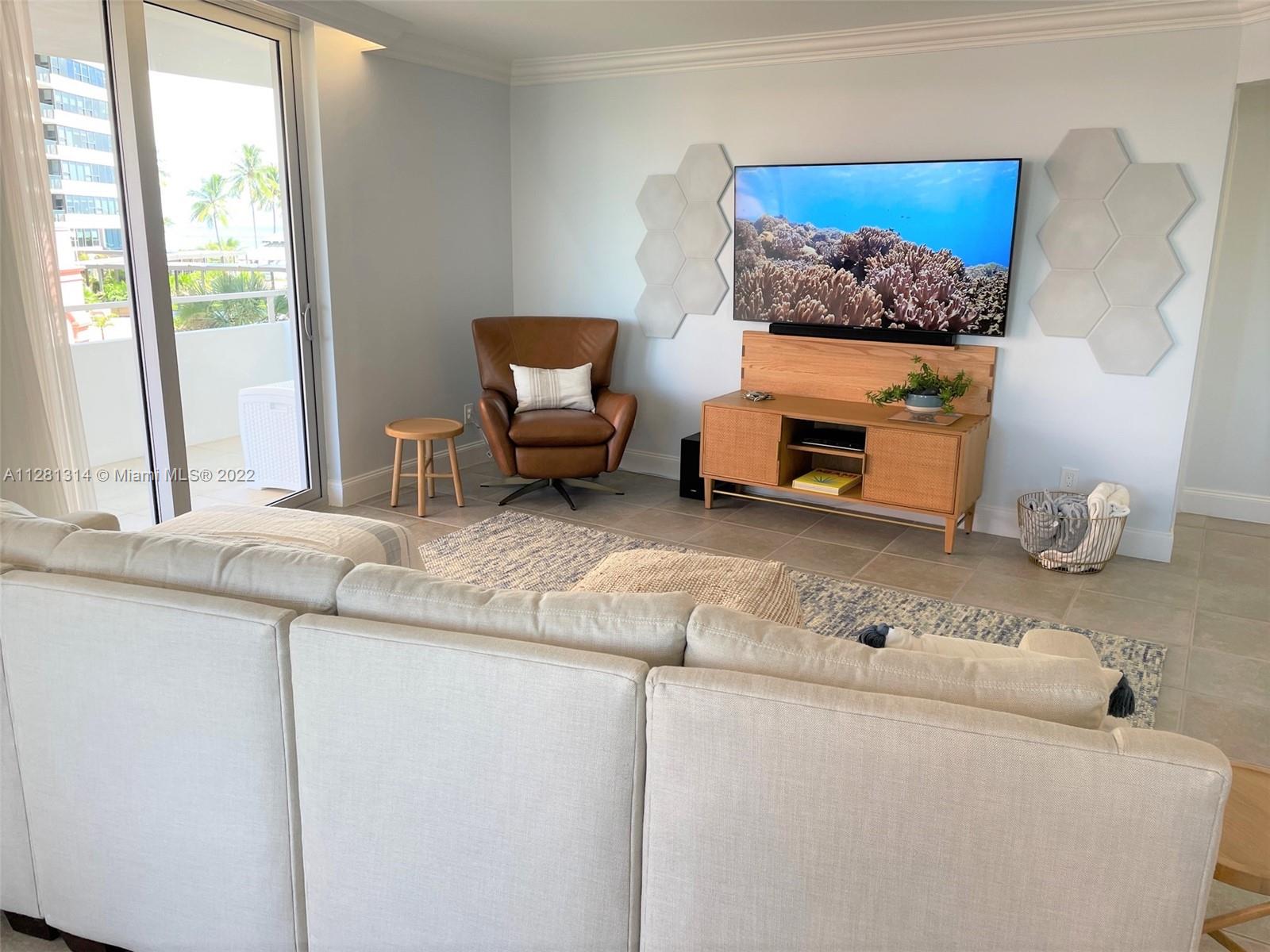 A living room features a large television, a leather armchair, and a light-colored sectional sofa — 5161 Collins Ave # 404, Miami Beach FL 33140, MIAMI BEACH, FL