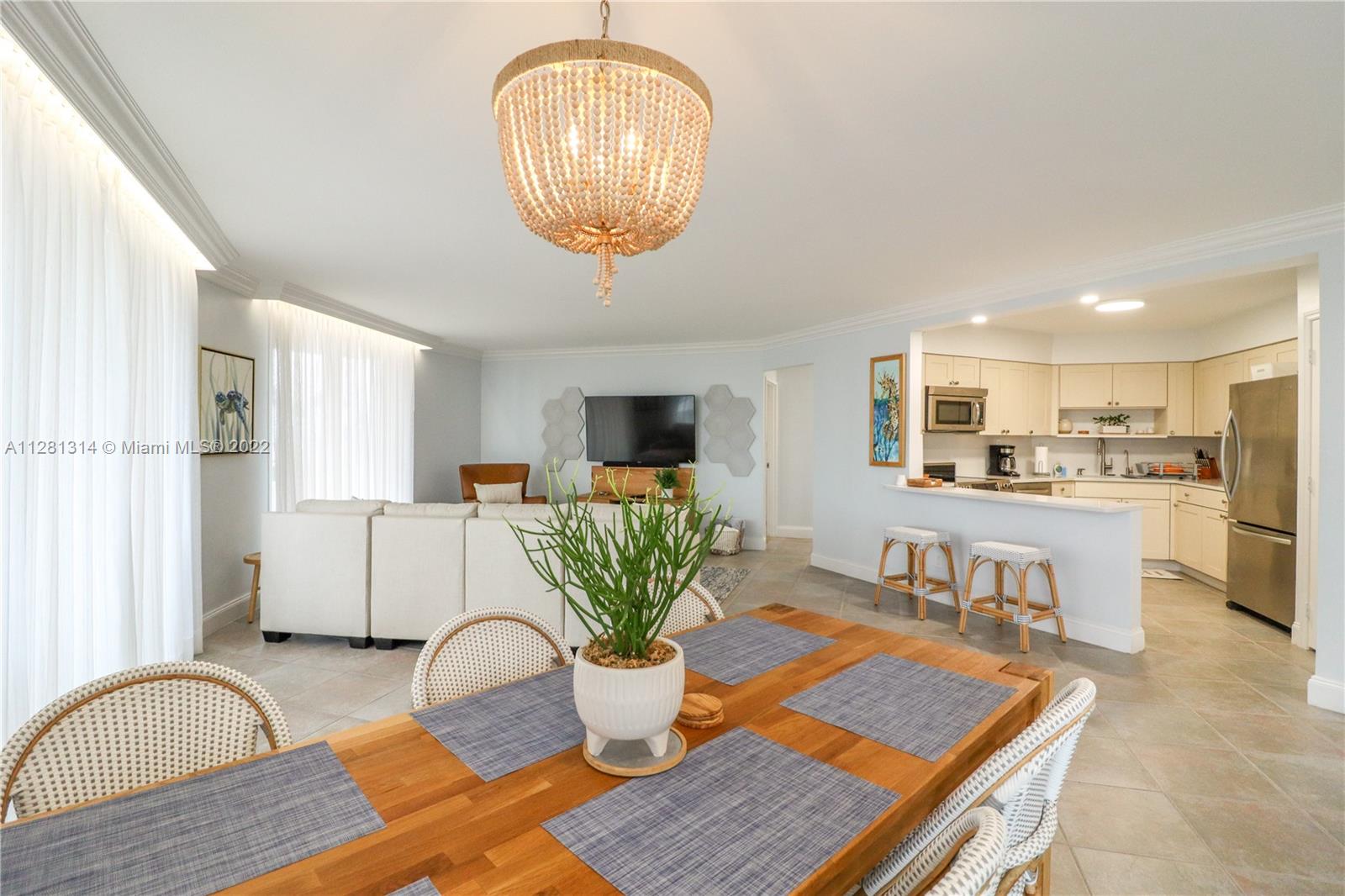 A dining area with a wooden table leads into an open-concept living room and kitchen — 5161 Collins Ave # 404, Miami Beach FL 33140, MIAMI BEACH, FL