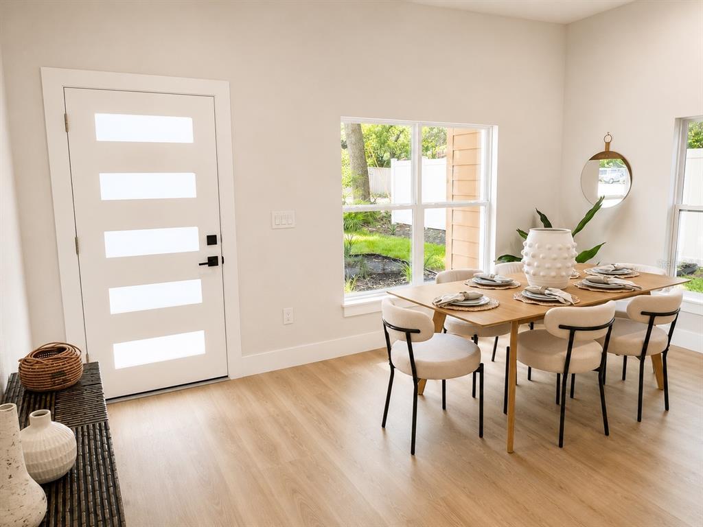 A dining room features a wooden table, modern chairs, a front door, and light flooring — 5808 N 16TH STREET, TAMPA, FL
