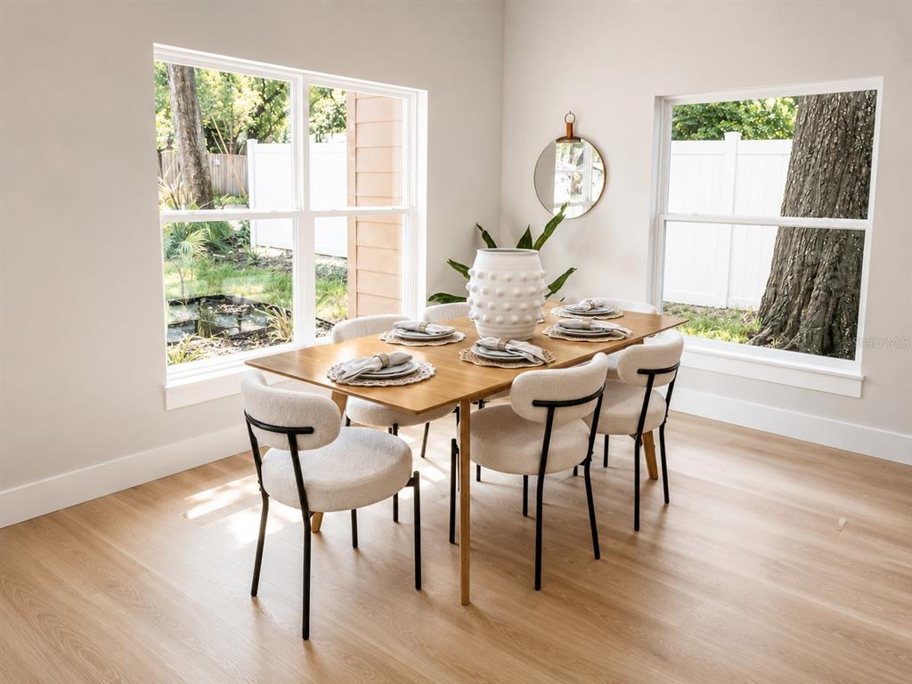 A dining room features a wooden table, six upholstered chairs, and large windows overlooking trees — 5808 N 16TH STREET, TAMPA, FL