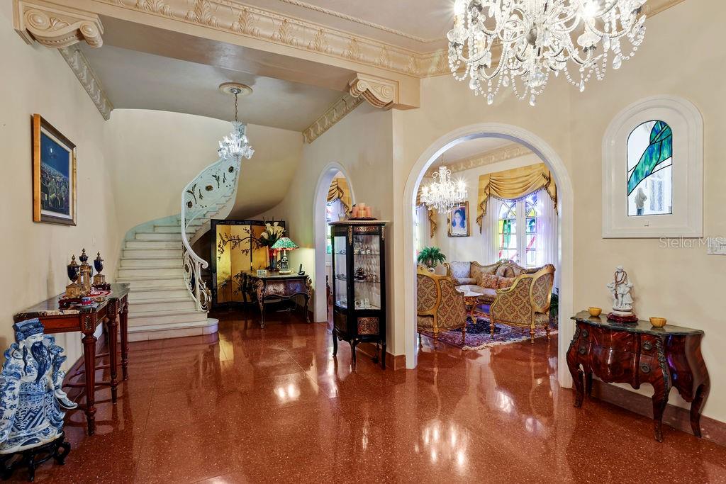 An elegant foyer features a curved staircase, polished stone floors, and ornate crystal chandeliers — 1404 VILA MAYO, SAN JUAN, PR