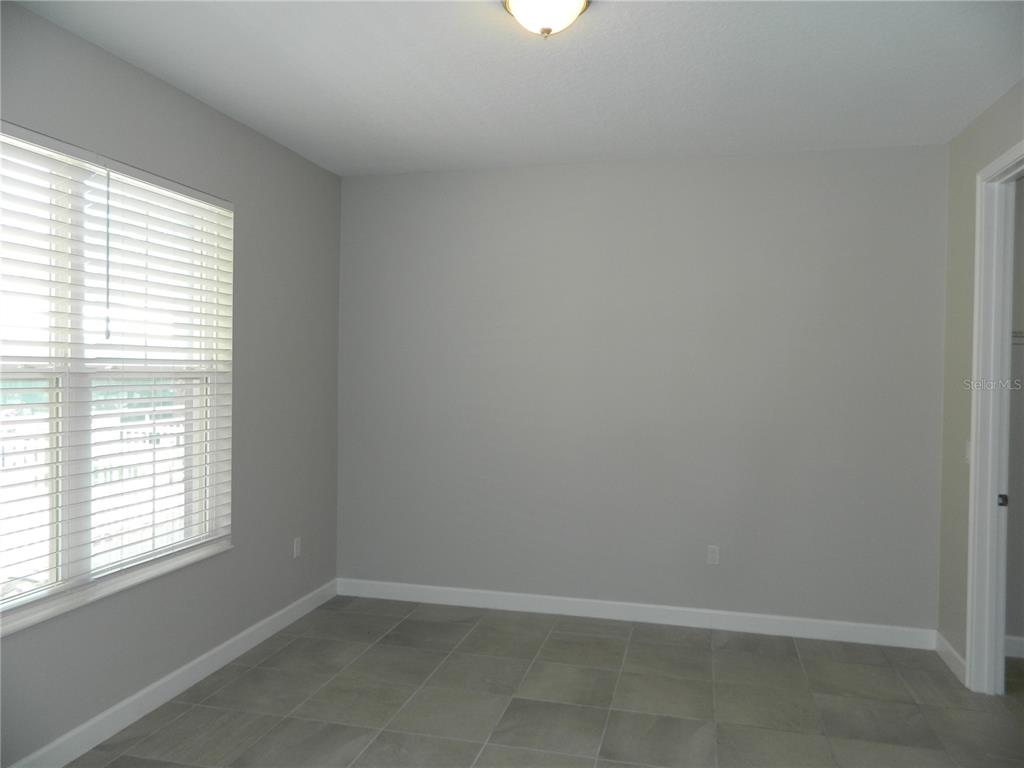 An empty room features gray walls, large square floor tiles, and a window with blinds — 1330 BOLTON PLACE, LAKE MARY, FL