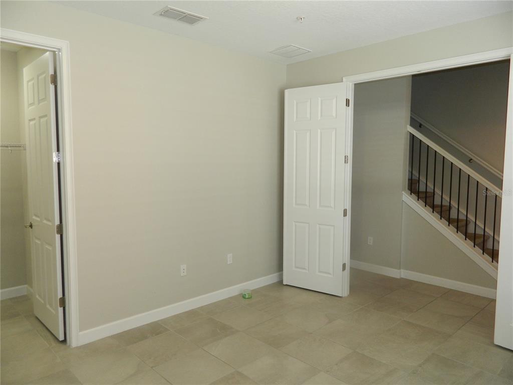 An interior room with light-colored tile flooring, beige walls, and an open doorway to stairs — 1330 BOLTON PLACE, LAKE MARY, FL