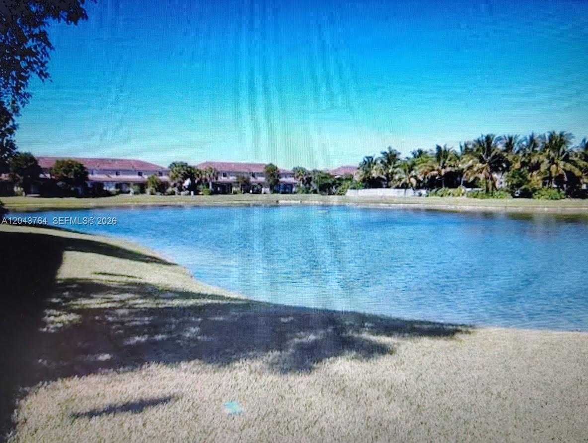 A view of a lake surrounded by grass, palm trees, and residential buildings — 8215 SW 27th St # 103, Miramar FL 33025, MIRAMAR, FL
