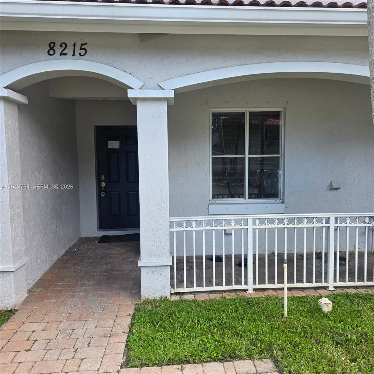 The exterior of a house features a brick walkway, a covered porch, and a white railing — 8215 SW 27th St # 103, Miramar FL 33025, MIRAMAR, FL