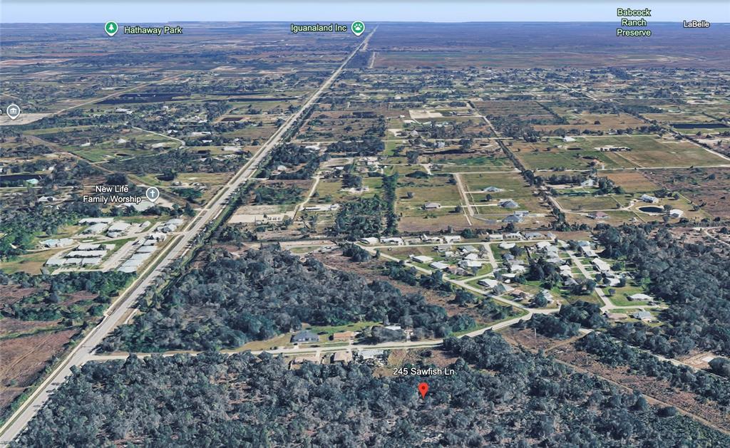 An aerial view shows a residential property surrounded by dense trees and nearby rural land — 245 SAWFISH LANE, PUNTA GORDA, FL