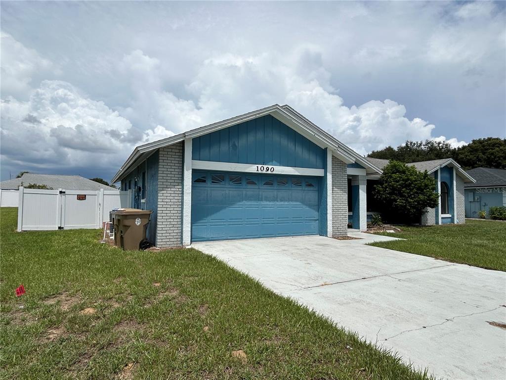 A single-story house features a blue garage, light brick siding, and a concrete driveway — 1090 JASON RIDGE COURT, KISSIMMEE, FL