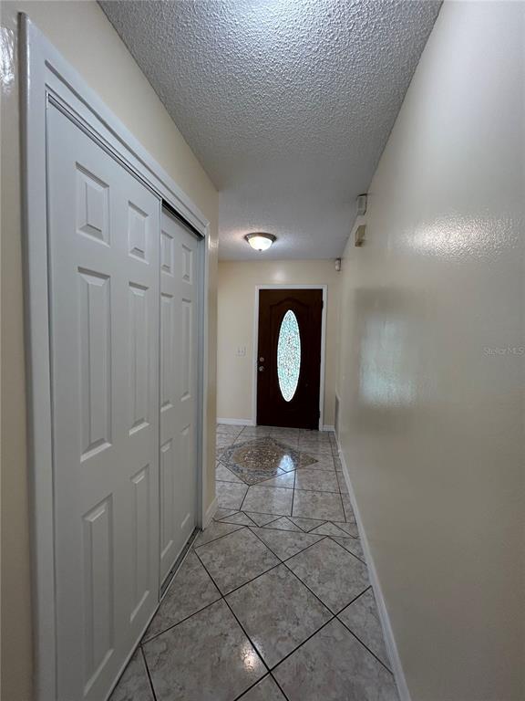 A tiled entryway features a white sliding closet door and a dark wood front door — 1090 JASON RIDGE COURT, KISSIMMEE, FL
