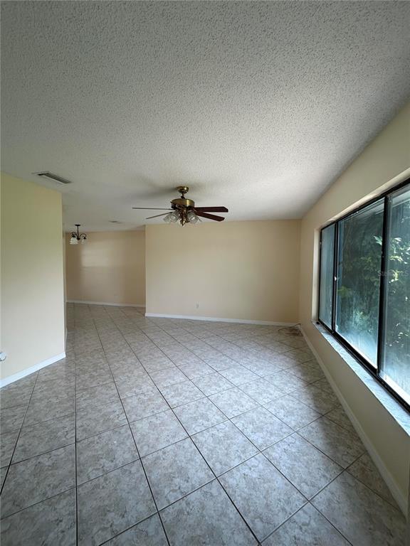 A room with light-colored tile flooring, a ceiling fan, and a large window — 1090 JASON RIDGE COURT, KISSIMMEE, FL