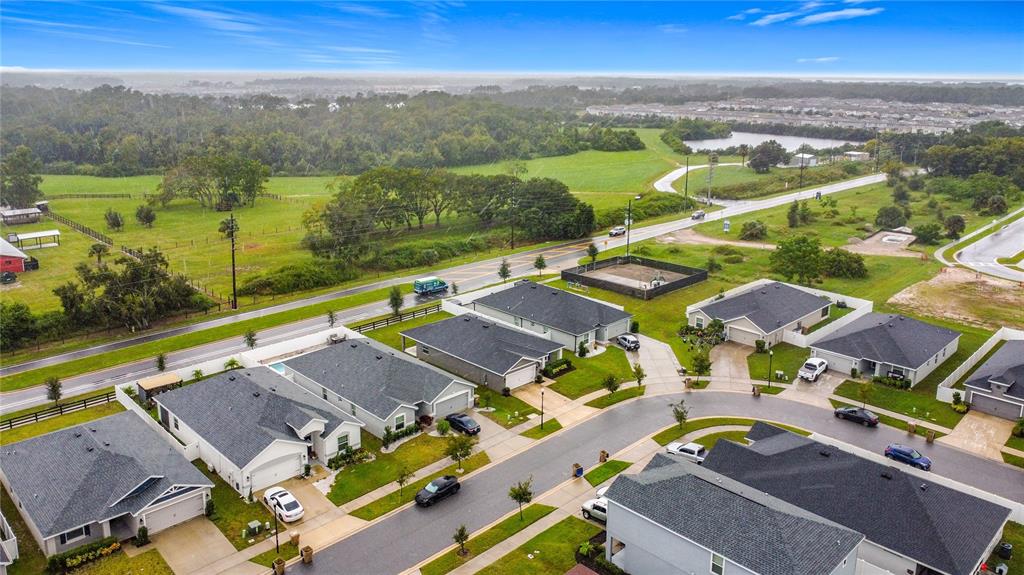 An aerial view shows a suburban neighborhood with single-family homes, paved streets, and surrounding green space — 190 POLERMO AVENUE, ST CLOUD, FL